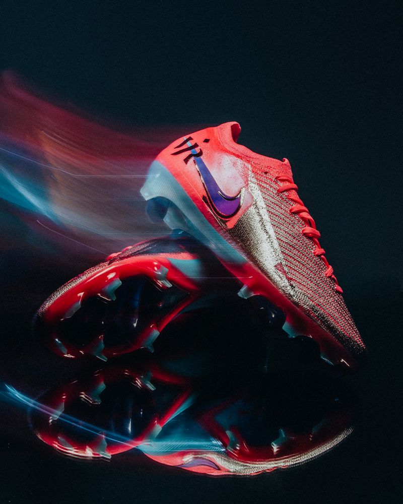 Red and silver Nike boot with red and blue light trails, reflected on black