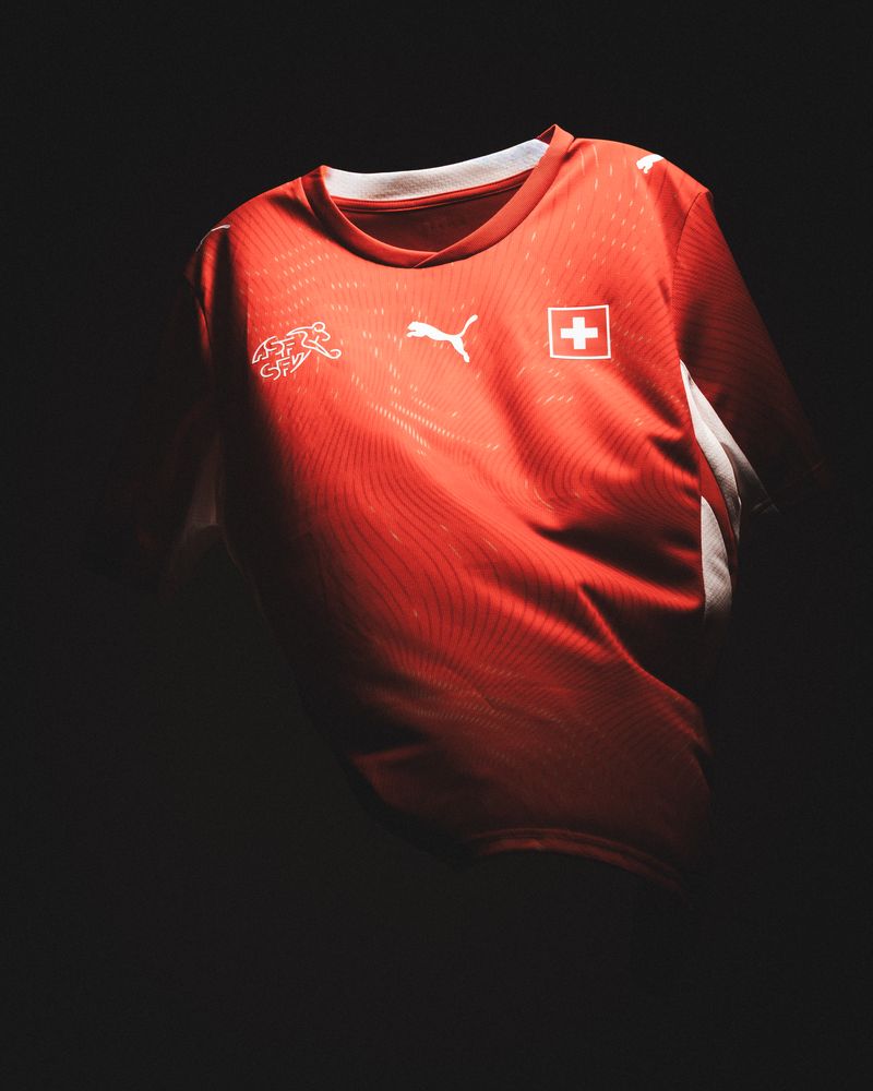 Red Puma Switzerland jersey lit by a narrow beam against black